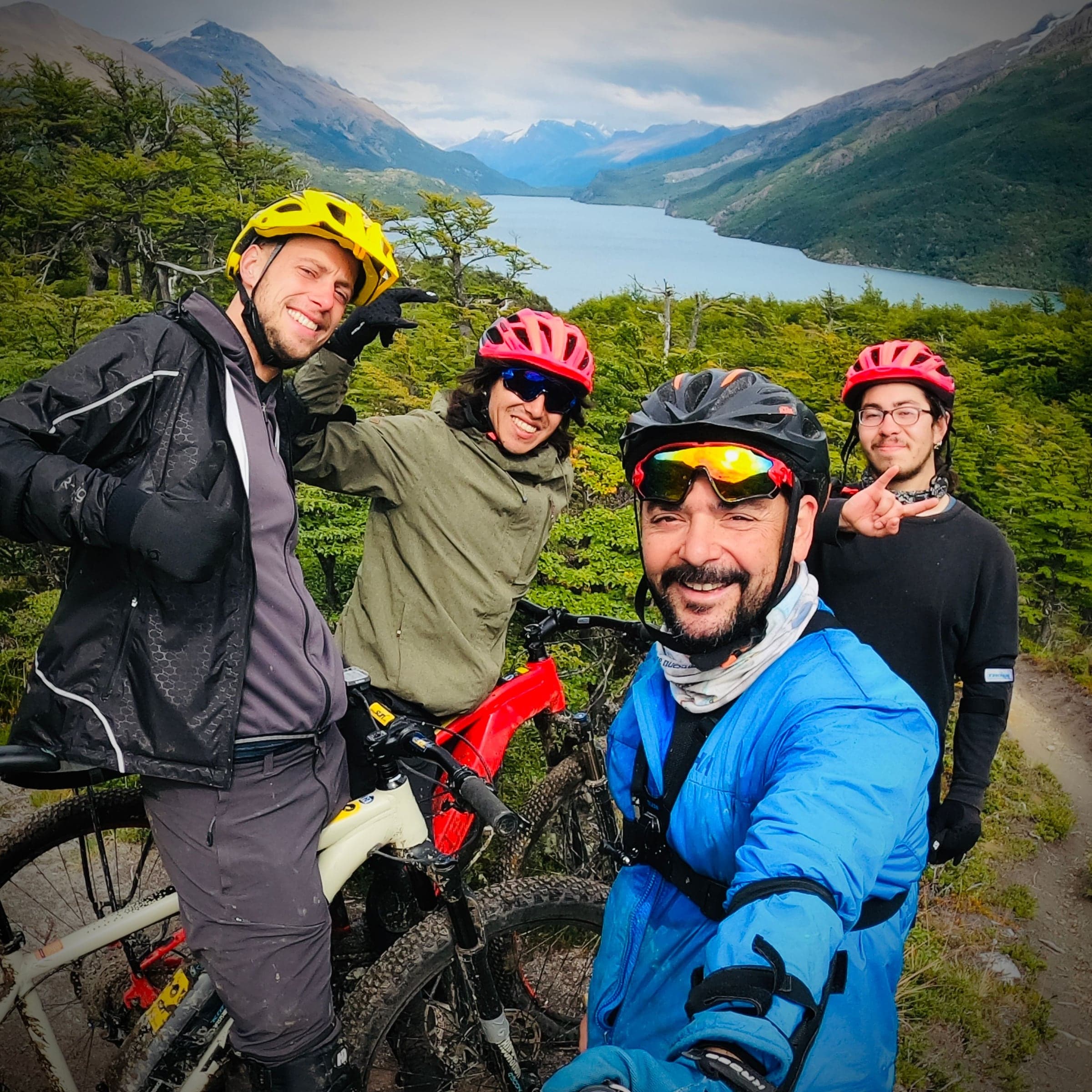 Un gruppo di ciclisti sorridenti con caschi ed e-bike, con il Lago del Desierto alle spalle