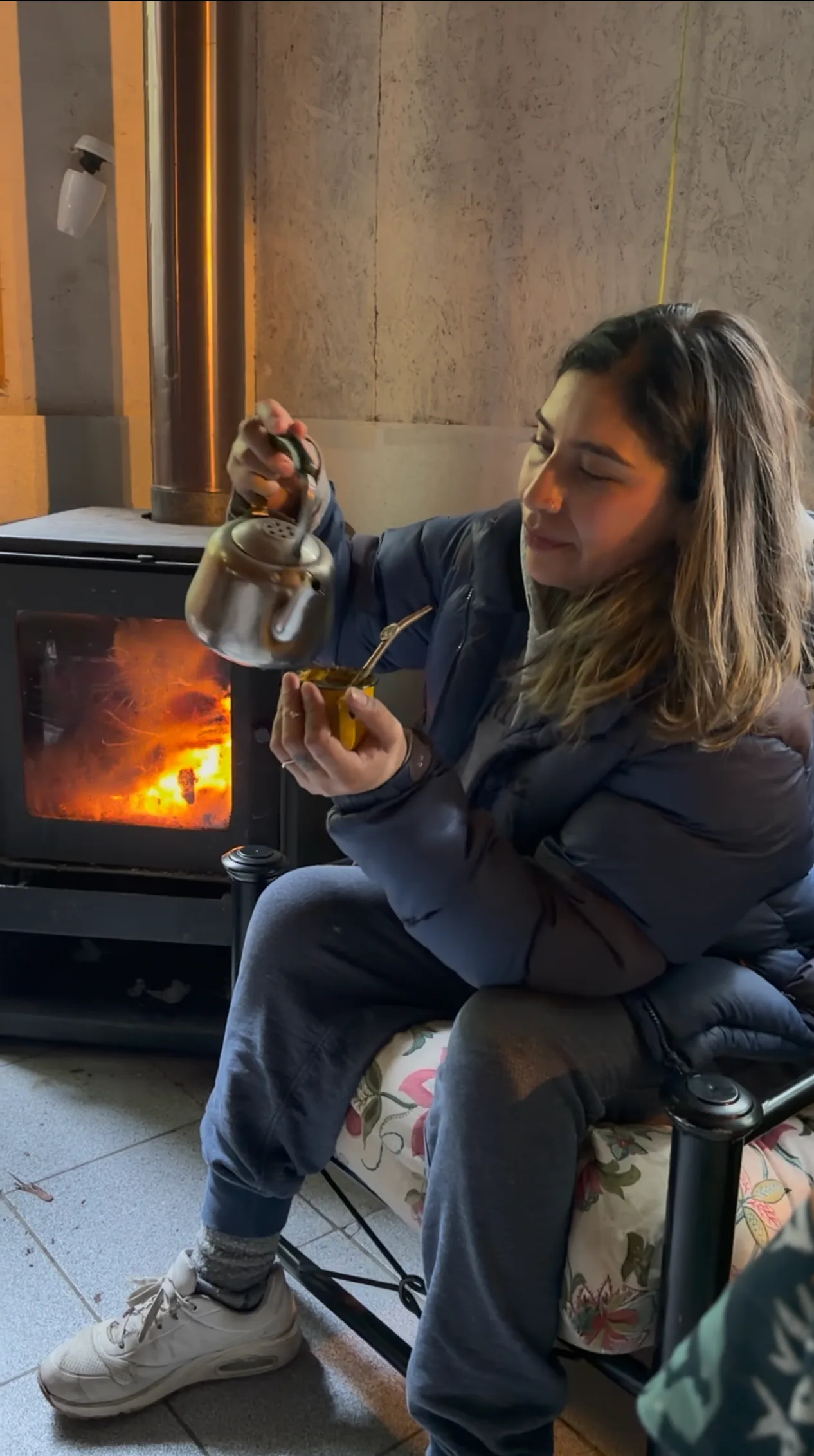 Katy prepara un mate accanto alla stufa a legna