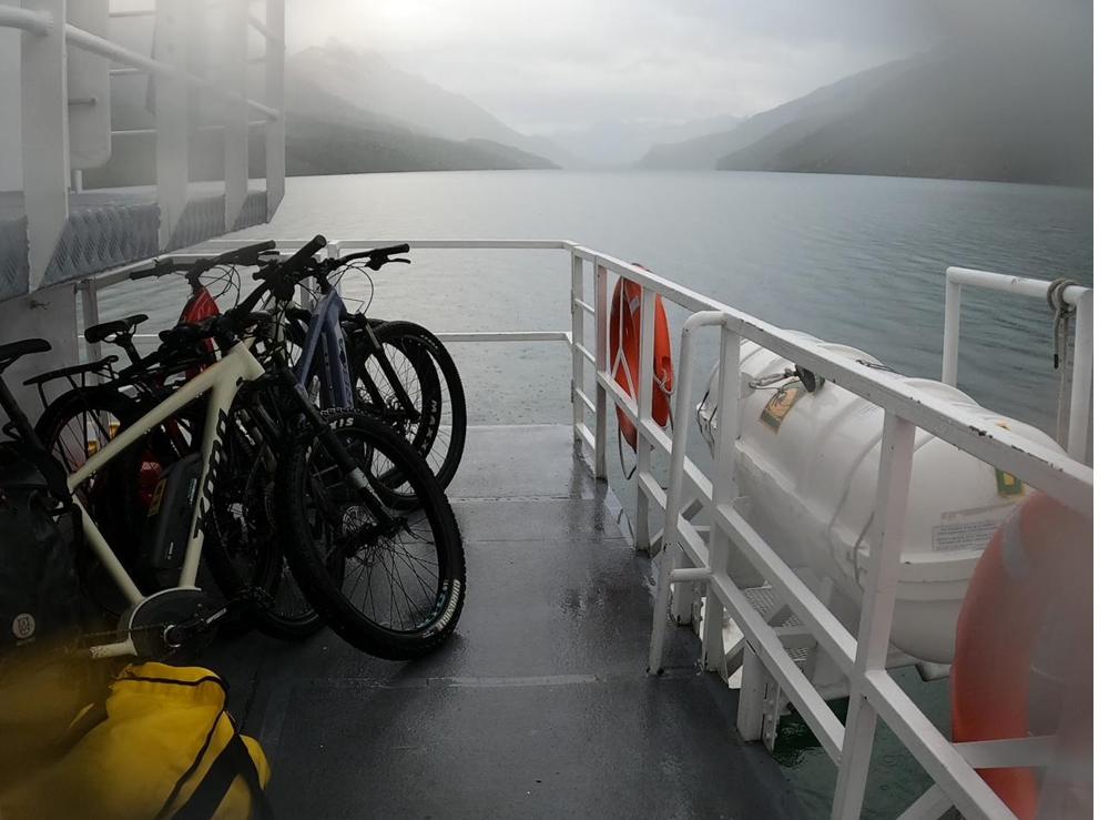 Bicicletas amarradas en la cubierta de una embarcación, con el lago cubierto de niebla
