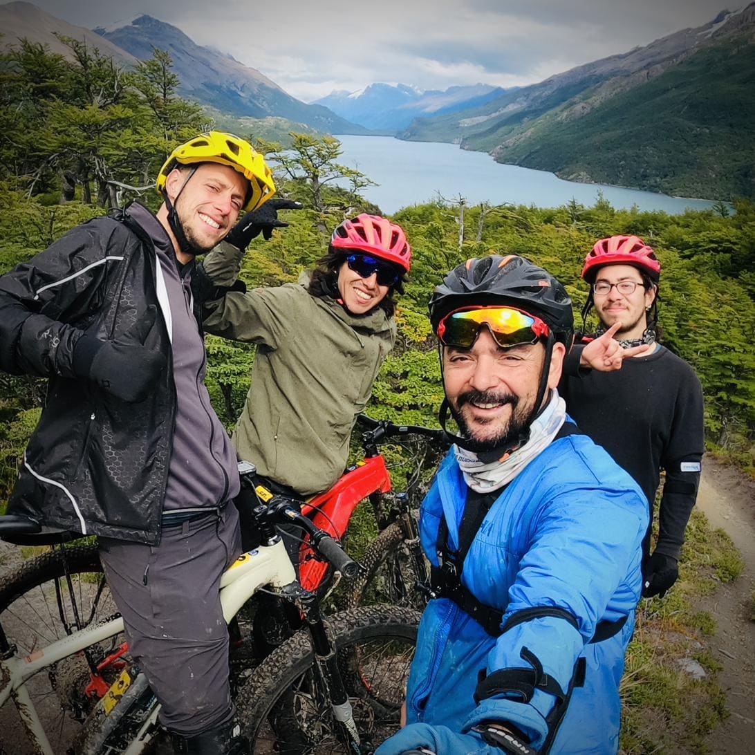 Un grupo de ciclistas sonrientes con cascos y e-bikes, con el Lago del Desierto detrás