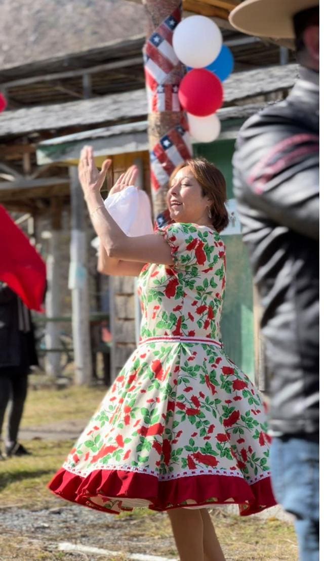 Una mujer baila cueca con vestido floreado en una celebración de Villa O'Higgins